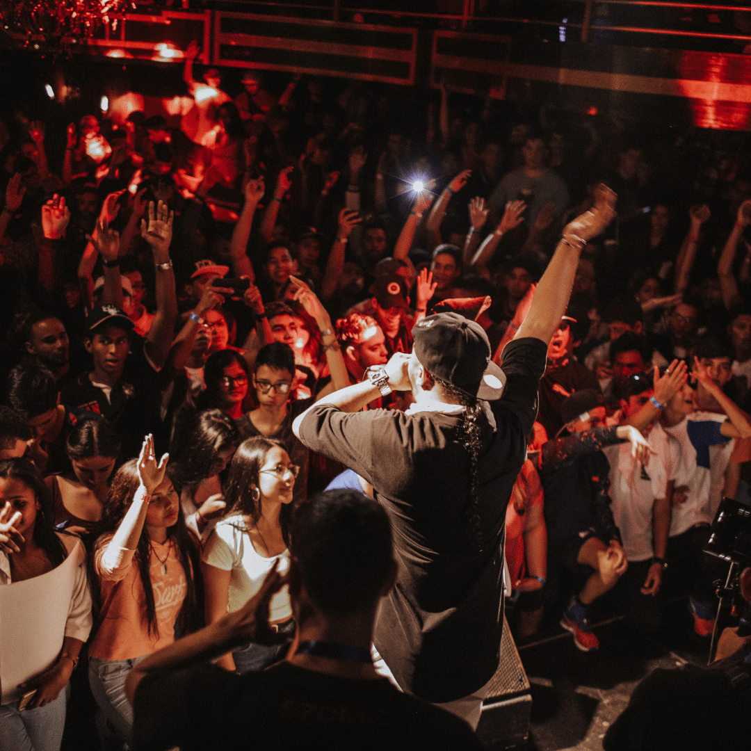 A singer signaling to the audience to raise their hands in the air during a concert.